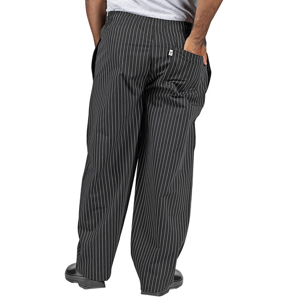A man wearing black and white pinstripe chef pants.