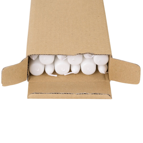 A cardboard box with Will & Baumer white taper candles inside.