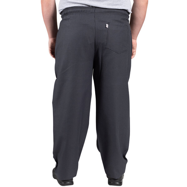 A person wearing Uncommon Chef black and gray houndstooth chef pants with a pocket.
