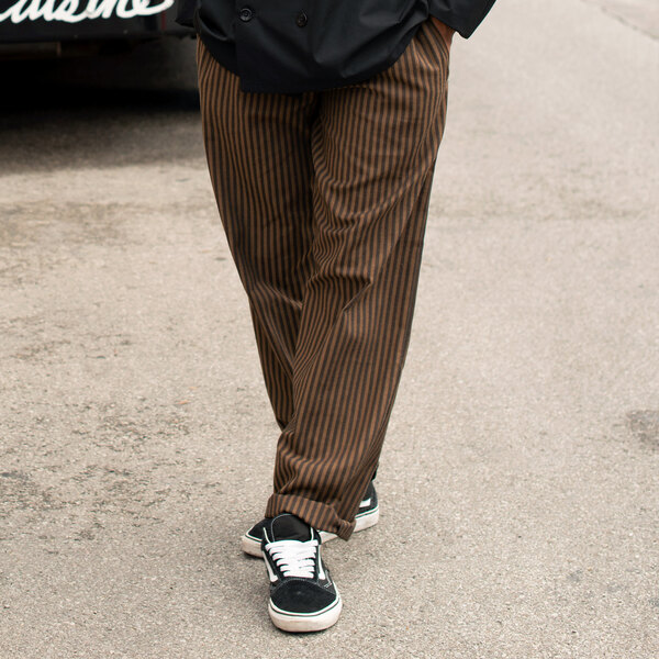 A person's legs in black and copper striped pants.