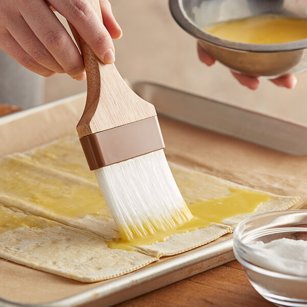 a person holding a brush over a pastry