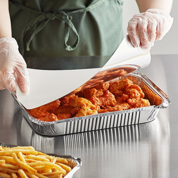 a person holding a foil tray of food