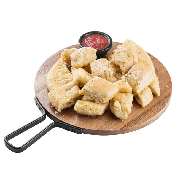 A Tablecraft acacia wood serving board with pizza, bread, and dipping sauce on a table.