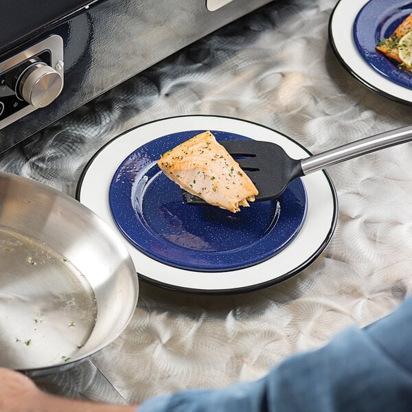 A close-up of a Tablecraft blue enamelware plate with food on it and a fork.