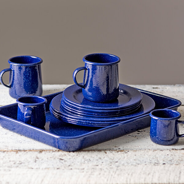 A blue speckled Tablecraft enamelware tray with blue speckled dishware and a mug on a white surface.