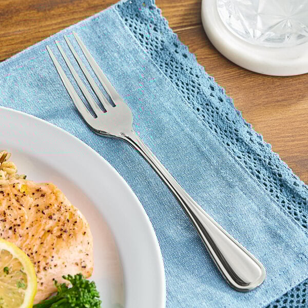 A Oneida New Rim stainless steel table fork next to a plate of food.