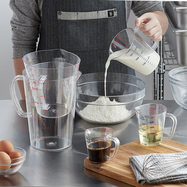 A person pouring milk into a clear measuring cup.