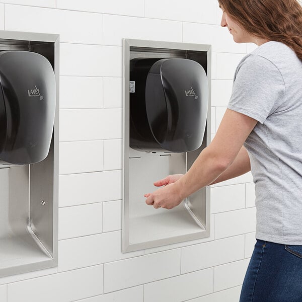a hand reaching out to a black paper towel dispenser