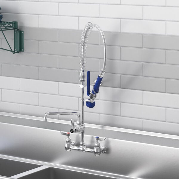 A Waterloo low profile wall-mounted pre-rinse faucet above a sink with an add-on faucet and hose.