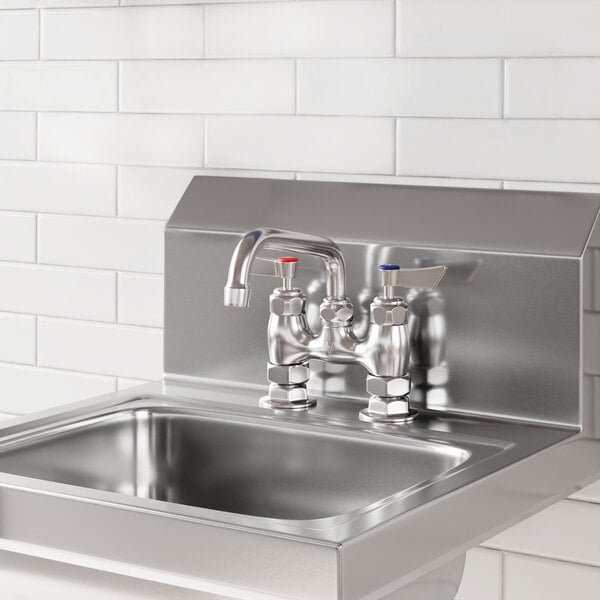 A stainless steel deck-mounted faucet with 4-inch centers and a 6-inch swing spout installed on a metal sink.