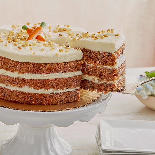 A Krusteaz carrot cake with a slice missing on a white stand.