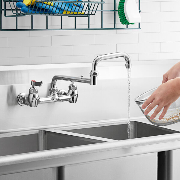 A hand using a Waterloo double-jointed swing spout to wash a bowl in a sink.