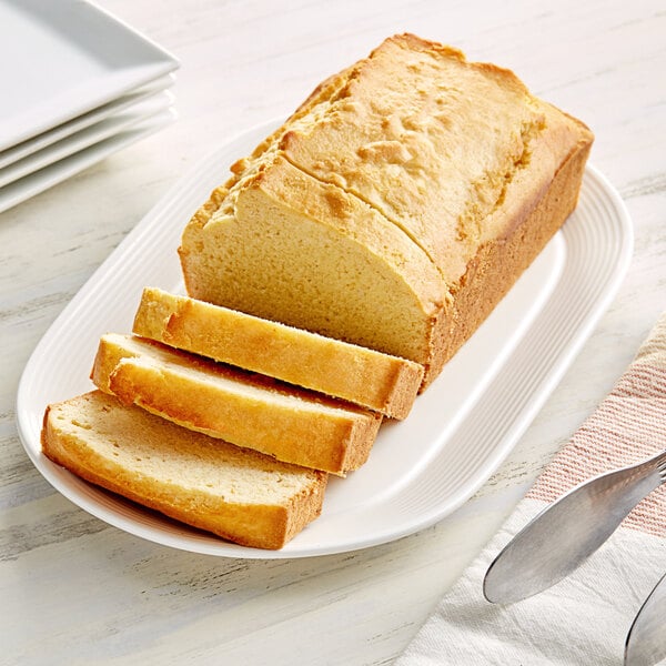 A loaf of Krusteaz Homestyle Cornbread on a plate with a piece cut off.