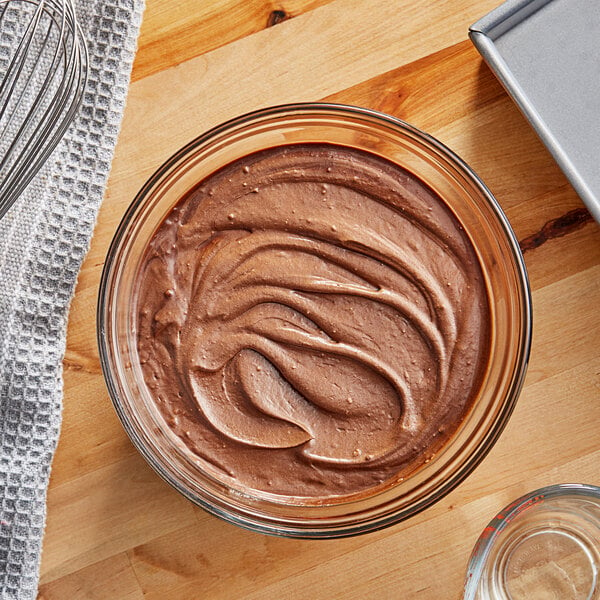 A glass bowl of brownie batter with a whisk.