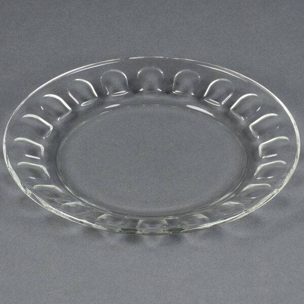 A clear glass Arcoroc salad plate with a circular design.