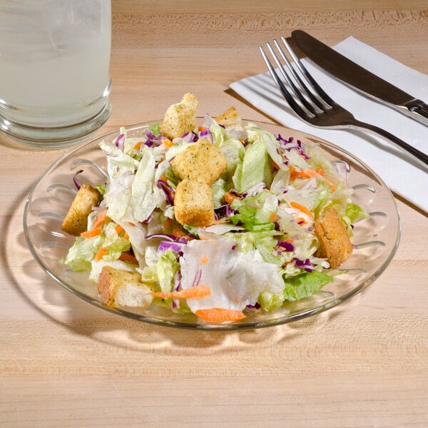 An Arcoroc glass salad plate with salad on it.