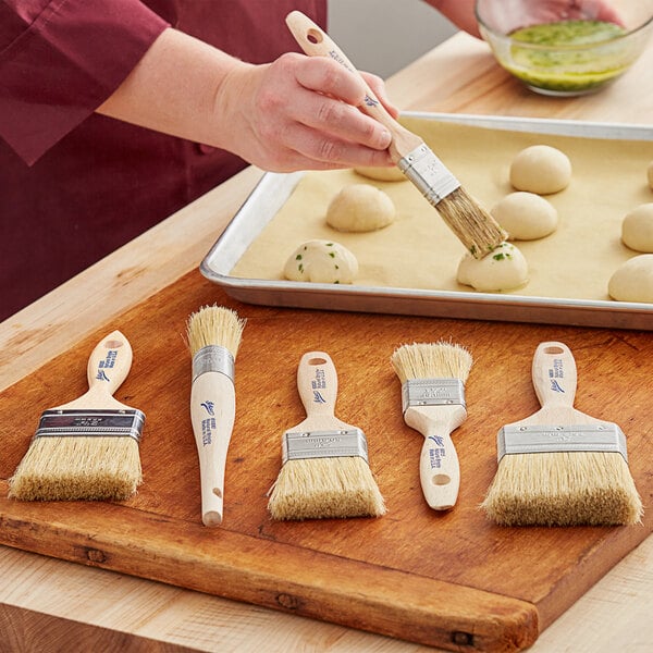 A person using an Ateco boar bristle brush to make food.