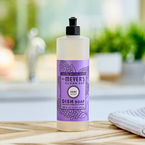 A bottle of Mrs. Meyer's lilac scented dish soap on a wooden counter.