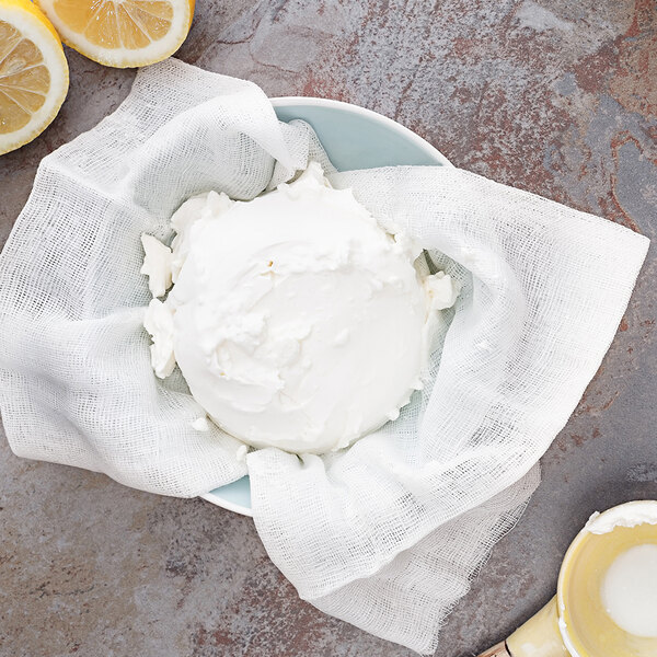 A yellow bowl of cream cheese with lemons and a spoon on a white background.