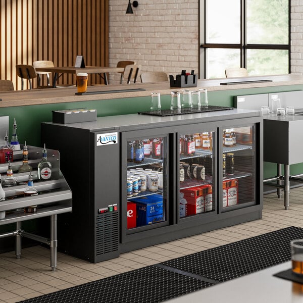 An Avantco back bar refrigerator with sliding glass doors filled with bottles of beer.