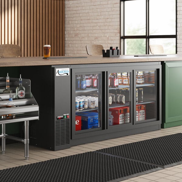 An Avantco back bar refrigerator with a galvanized top and glass sliding doors filled with drinks on a counter.