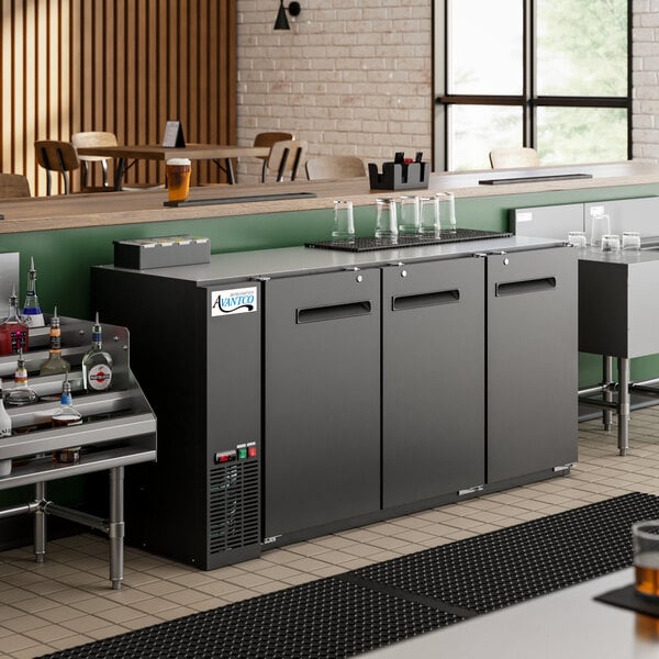 An Avantco back bar refrigerator with a galvanized top and LED lighting under a bar counter with bottles on it.
