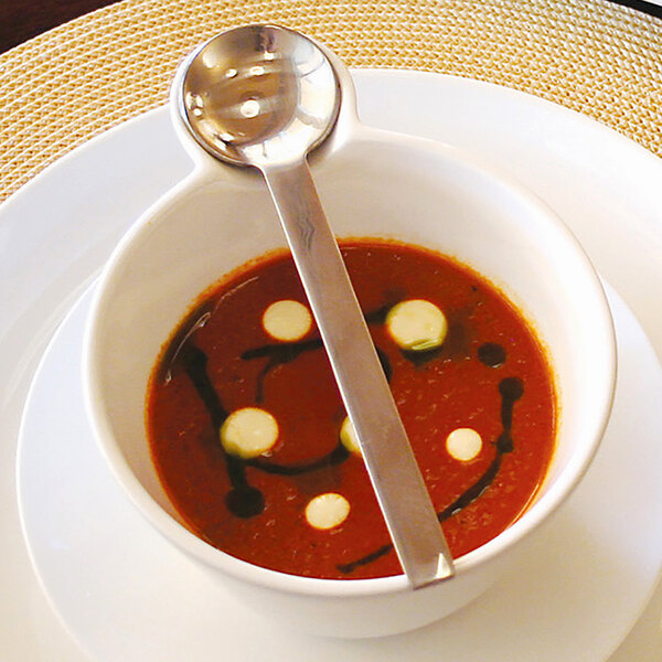 The front of a stainless steel demitasse spoon in a bowl of soup.