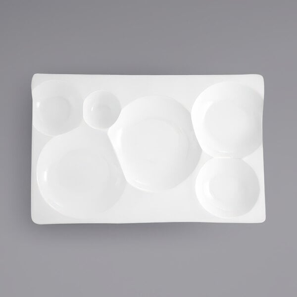 A close-up of a white rectangular porcelain platter with six compartments.