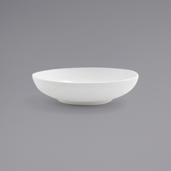 A Front of the House Harmony bright white low round porcelain bowl on a gray surface.