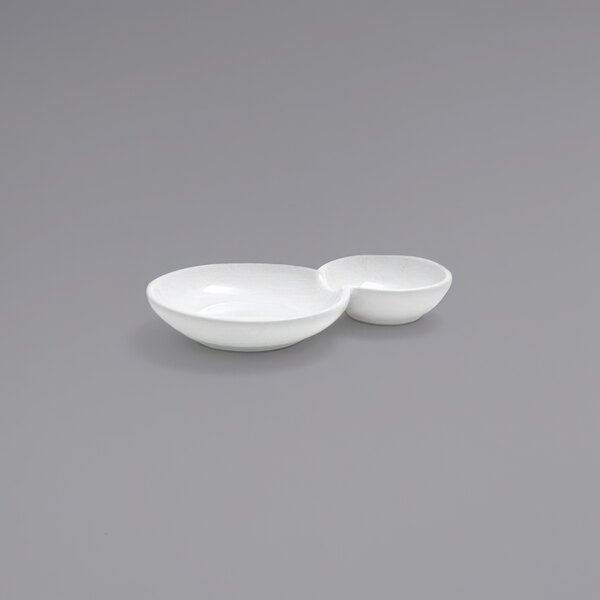 A bright white porcelain plate with two compartments.