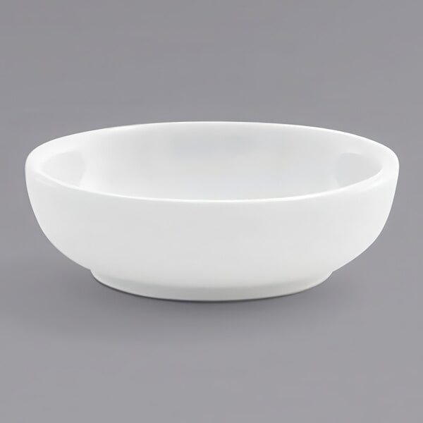 A Front of the House bright white porcelain ramekin on a gray surface.