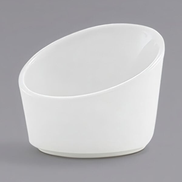 A white slanted porcelain sauce cup on a gray background.