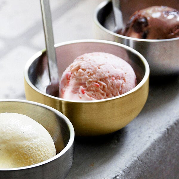 A group of Front of the House Harmony Matte Brass Brushed Stainless Steel double wall bowls filled with ice cream.