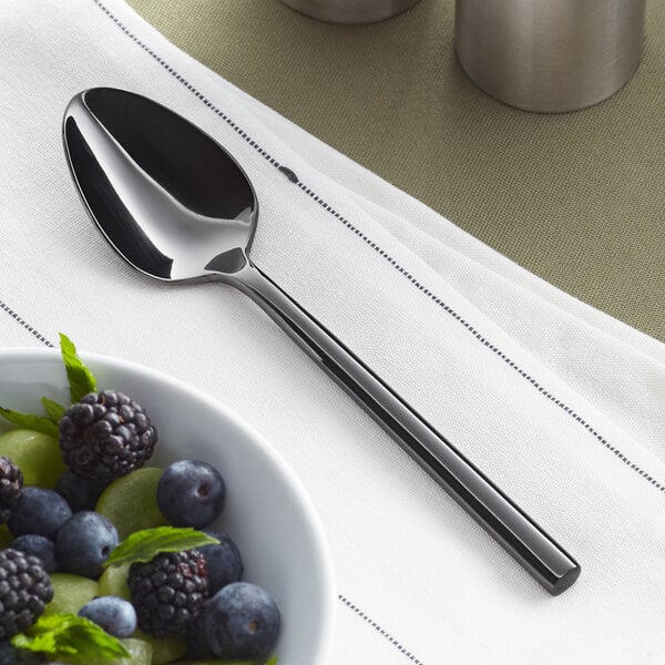 An Acopa Phoenix stainless steel teaspoon next to a bowl of fruit.