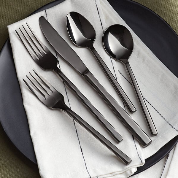 A black plate with Acopa Phoenix black stainless steel spoons on it.
