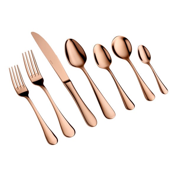 A set of seven rose gold-colored utensils, including two forks, a knife, and four spoons, arranged in a row on a white background.