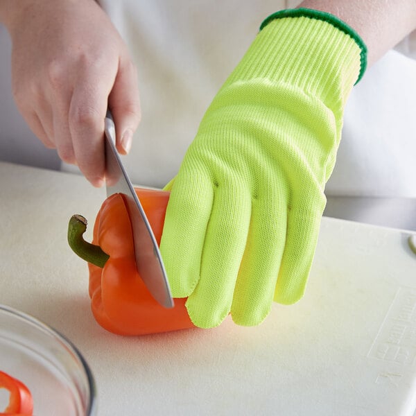 A person wearing yellow Mercer Culinary Millennia kitchen gloves cutting a bell pepper with a knife.
