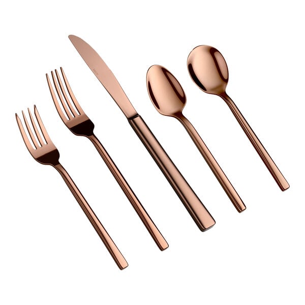 Five pieces of rose gold-colored flatware, including two forks, a knife, and two spoons, are arranged side by side on a white background.