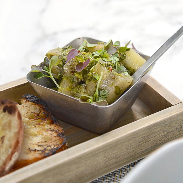 A white bowl of food with a Front of the House stainless steel ramekin on a table.