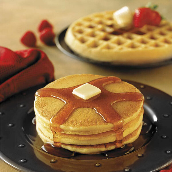 A stack of Krusteaz Buttermilk Pancakes with syrup and butter on top.