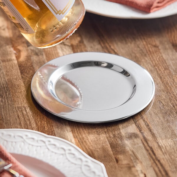 A mirror-finished stainless steel wine coaster or spoon rest on a wooden table.