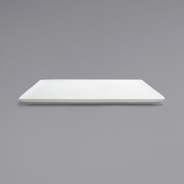 A Front of the House bright white square porcelain plate on a gray surface.