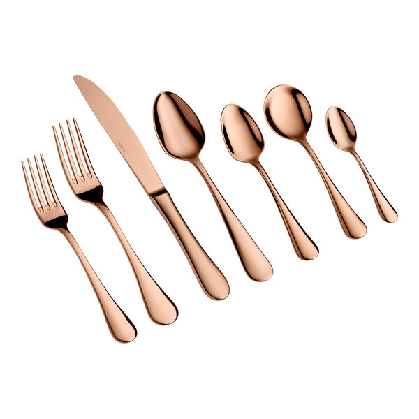 A set of seven rose gold-colored utensils, including two forks, a knife, and four spoons, arranged in a row on a white background.