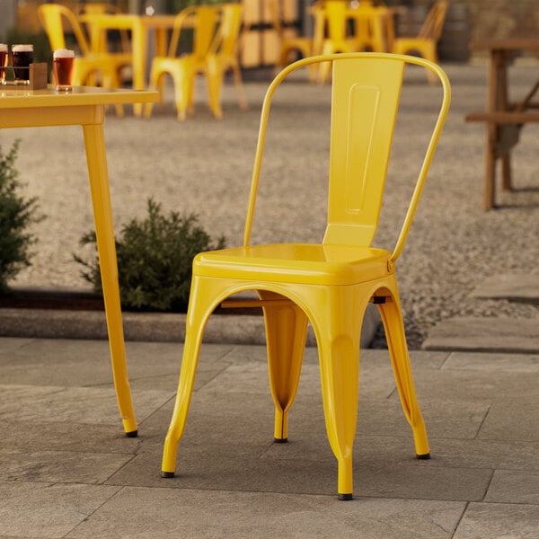 A yellow Lancaster Table & Seating outdoor cafe chair on a stone patio.