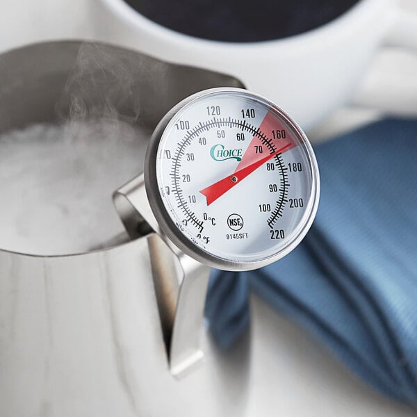 Frothing thermometer in a frothing pitcher full of steamed milk