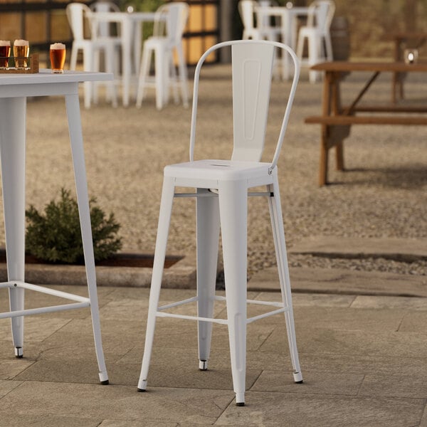 A white Lancaster Table & Seating outdoor cafe barstool at a table with drinks.