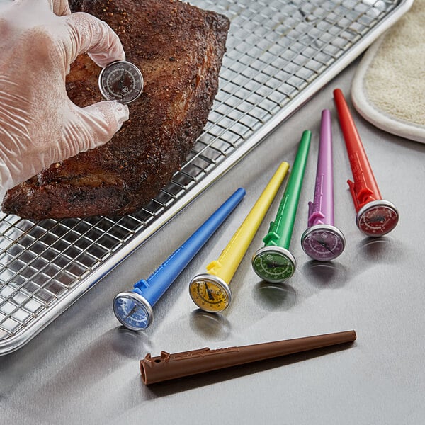 A person using an AvaTemp HACCP pocket probe dial thermometer to gauge the temperature of meat in a professional kitchen.