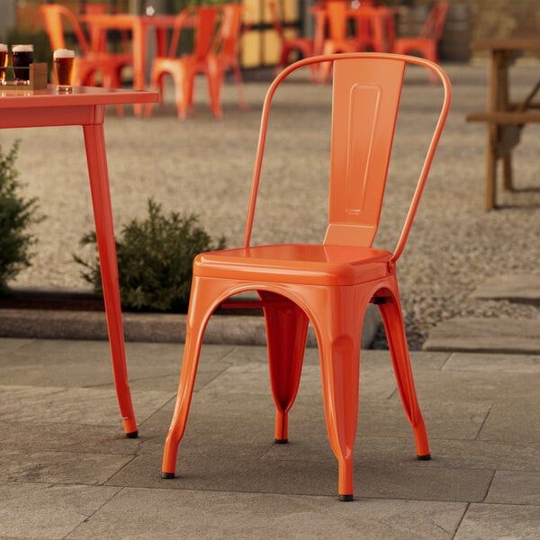 A Lancaster Table & Seating orange chair sits on an outdoor patio.