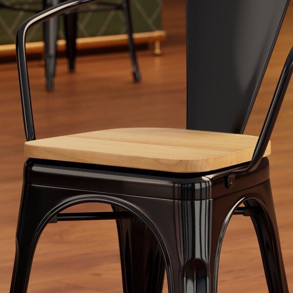 A Lancaster Table & Seating black metal chair with a natural wood seat.