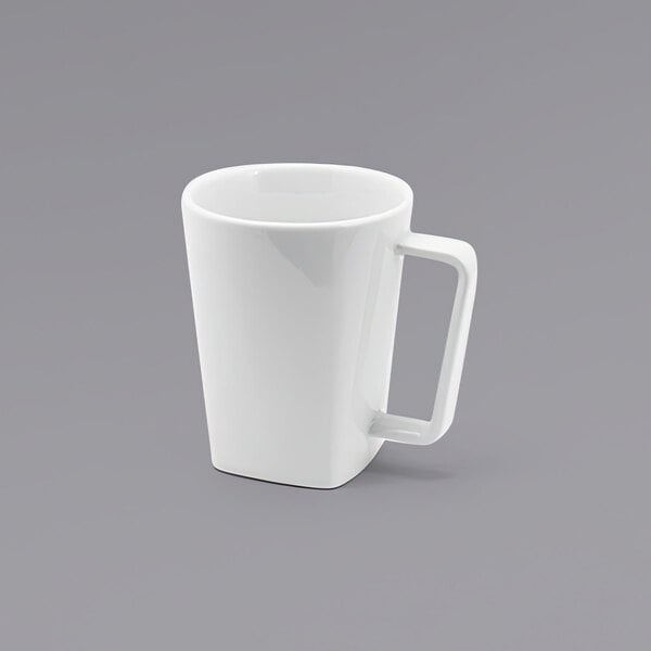 A close up of the front of a white porcelain mug with a handle.